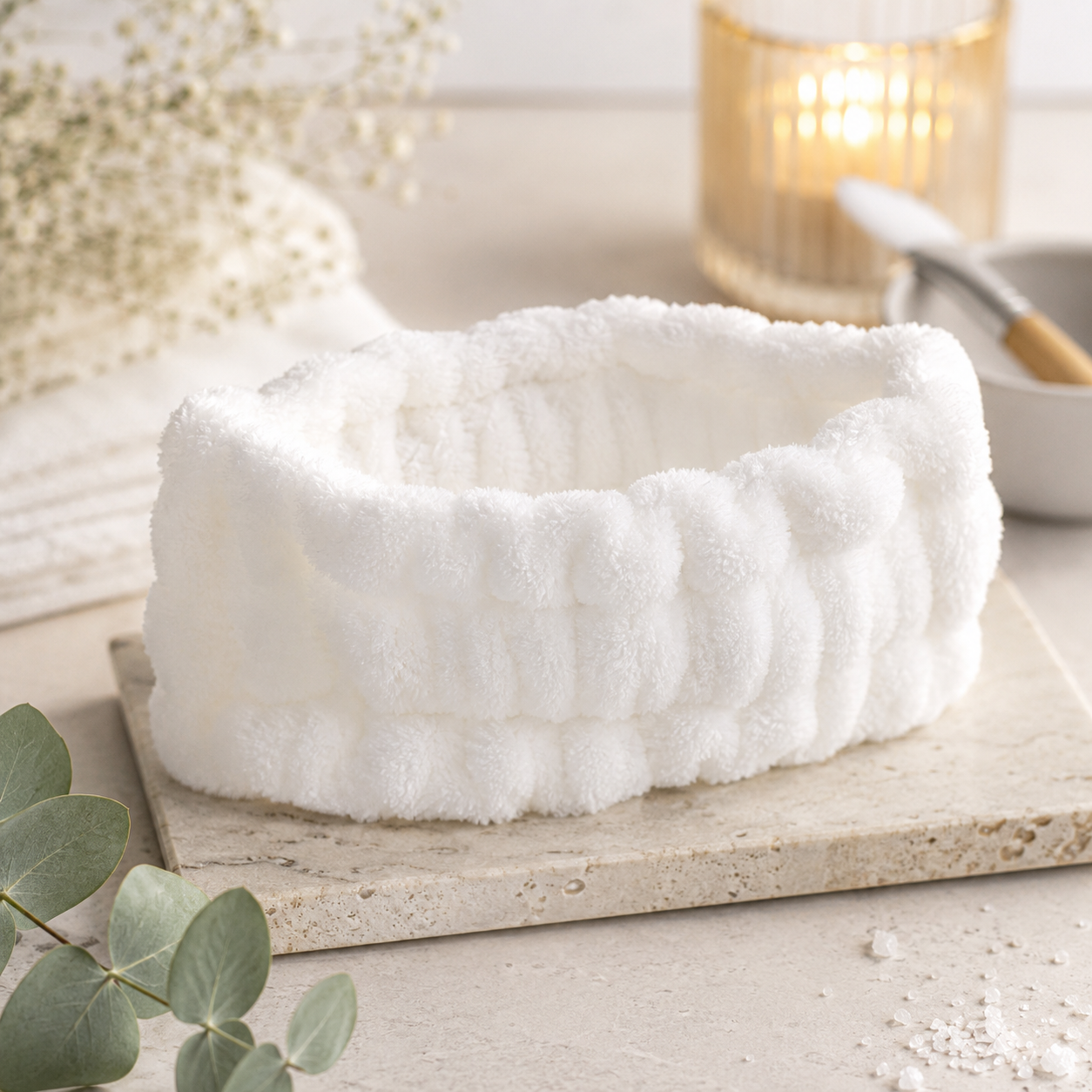Luxury Spa Headband in white plush terry cloth, styled on a marble tray with eucalyptus and a glowing candle